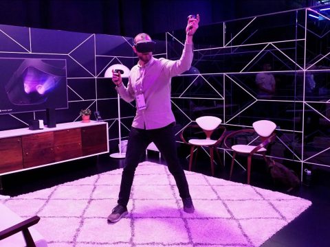 Man using VR headset in a purple room.