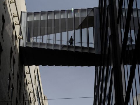 Man standing on a glass bridge looking down
