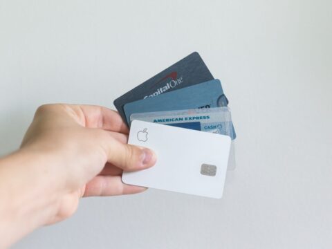 A hand holding four payment cards in a fan fashion